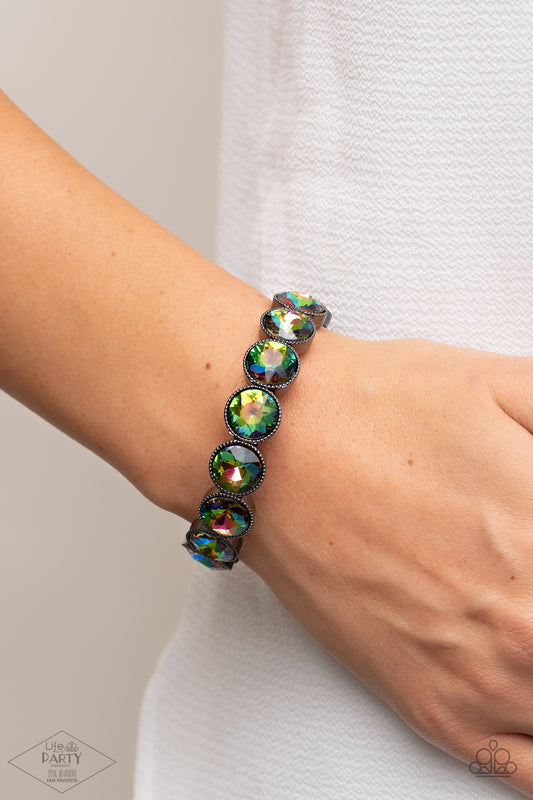 Faceted oil spill gems are pressed into sleek gunmetal frames. The glittery frames are threaded along stretchy bands, creating a glamorous look around the wrist.